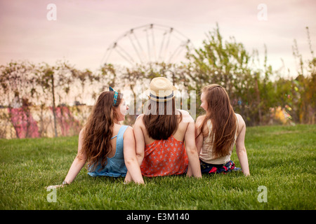 Rückseite Blick auf drei junge Frauen (18-19) sitzen auf dem Rasen Stockfoto