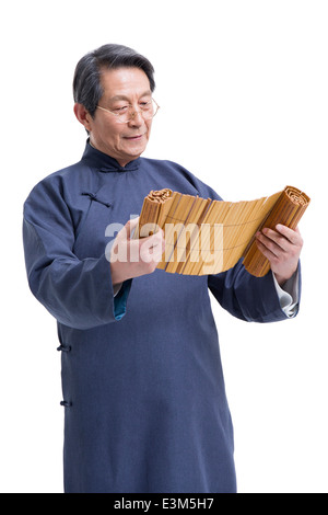 Oberlehrer in traditioneller Kleidung Lesung Bambus rutscht Stockfoto