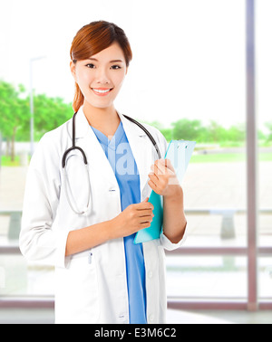 Hübsche junge Ärztin stehen und halten Dokument Stockfoto