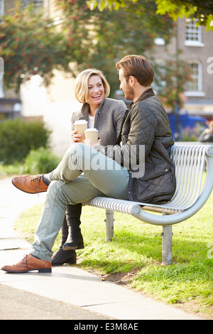 Paar erholsame auf Parkbank mit Kaffee zum mitnehmen Stockfoto