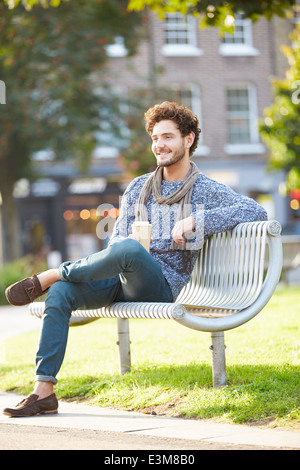 Mann auf der Parkbank mit Kaffee zum mitnehmen Stockfoto