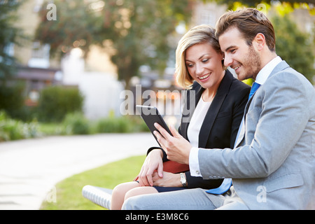 Business-paar mit Digital-Tablette auf Parkbank Stockfoto