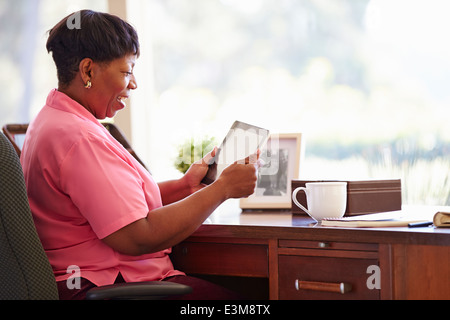 Reife Frau mit Digital-Tablette auf Schreibtisch zu Hause