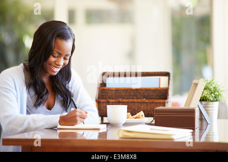 Frau schriftlich Notebook am Schreibtisch Stockfoto