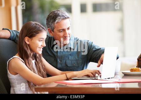 Vater und Tochter im Teenageralter Blick auf Laptop zusammen Stockfoto