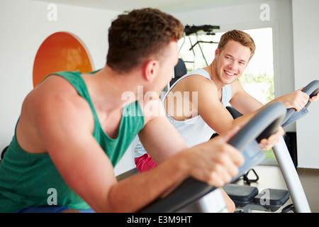 Zwei junge Männer Training im Fitness-Studio zum Radfahren Maschinen zusammen Stockfoto