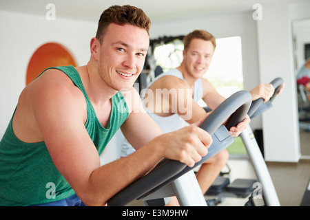 Zwei junge Männer Training im Fitness-Studio zum Radfahren Maschinen zusammen Stockfoto