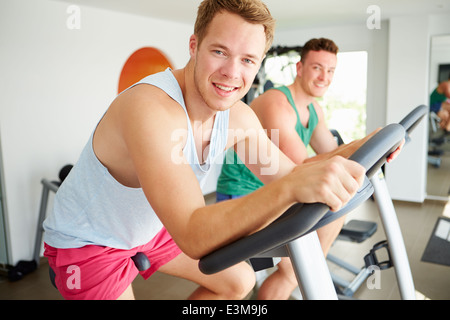 Zwei junge Männer Training im Fitness-Studio zum Radfahren Maschinen zusammen Stockfoto