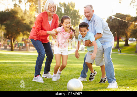 Großeltern spielen Fußball mit Enkelkindern im Park Stockfoto