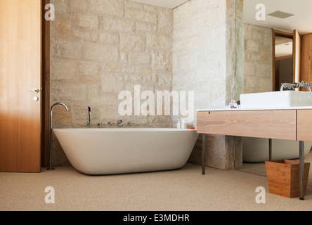 Steinwand hinter der Badewanne im modernen Badezimmer Stockfoto