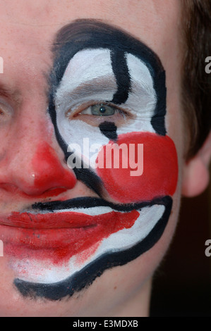 Teenager mit Hälfte seines Gesichts gemalt als Clown. Stockfoto