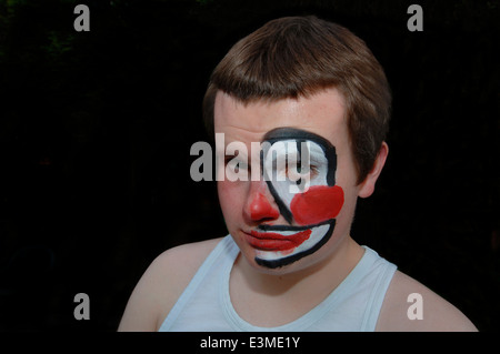 Teenager mit Hälfte seines Gesichts gemalt als Clown. Stockfoto