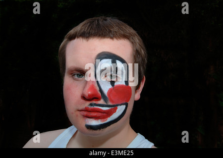 Teenager mit Hälfte seines Gesichts gemalt als Clown. Stockfoto