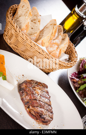 Lecker gegrilltes Rindersteak mit einem gezwirbelten Stück Butter und ein Zweig frischer Rosmarin garniert und serviert auf einem weißen Teller, enge u Stockfoto