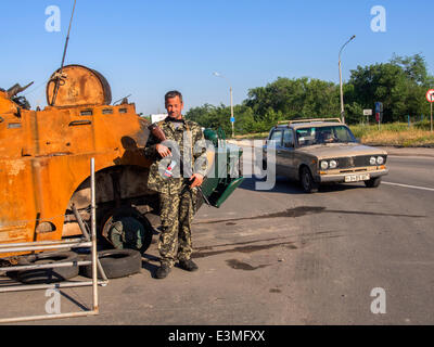 Oleksandrivs'k, Luhans'ka Oblast, Ukraine. 24. Juni 2014. Bewaffneten prorussischen Rebellen posiert vor dem Hintergrund der abgestürzten gepanzerten Nationalgarde der Ukraine am Checkpoint in der Oleksandrivs'k Stadt, Luhans'ka Oblast---wegen zahlreiche terroristische Angriffe auf die Position des ukrainischen Truppen, die 24. Juni 2014 von Mi-8 Hubschrauber, getroffen wurde neun ukrainische Militär zu töten. Als Folge dieses und andere terroristische Anschläge Präsident der Ukraine Petro Poroschenko nicht ausgeschlossen, dass ein Waffenstillstand vorzeitig abgebrochen werden kann. Bildnachweis: Igor Golovnov/Alamy Live-Nachrichten Stockfoto