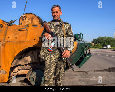 Oleksandrivs'k, Luhans'ka Oblast, Ukraine. 24. Juni 2014. Bewaffneten prorussischen Rebellen posiert vor dem Hintergrund der abgestürzten gepanzerten Nationalgarde der Ukraine am Checkpoint in der Oleksandrivs'k Stadt, Luhans'ka Oblast---wegen zahlreiche terroristische Angriffe auf die Position des ukrainischen Truppen, die 24. Juni 2014 von Mi-8 Hubschrauber, getroffen wurde neun ukrainische Militär zu töten. Als Folge dieses und andere terroristische Anschläge Präsident der Ukraine Petro Poroschenko nicht ausgeschlossen, dass ein Waffenstillstand vorzeitig abgebrochen werden kann. Bildnachweis: Igor Golovnov/Alamy Live-Nachrichten Stockfoto