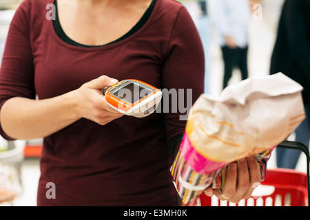 Mittelteil der Frau scannen Produkt mit Barcode-Leser im Supermarkt Stockfoto