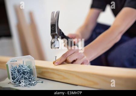 Mittelteil des weiblichen Zimmermann Hämmern Nagel in Holzbrett Stockfoto