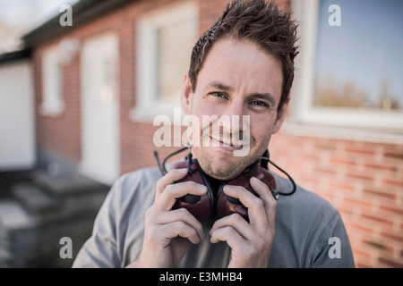 Porträt von zuversichtlich Zimmermann mit Gehörschutz um Hals auf Baustelle Stockfoto