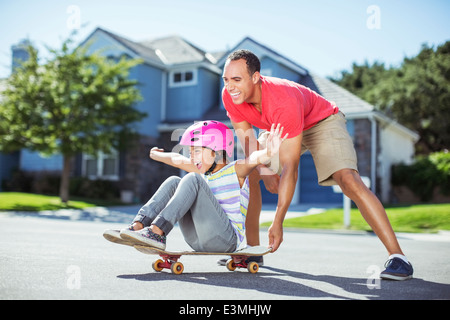 Vater drängen Tochter auf skateboard Stockfoto