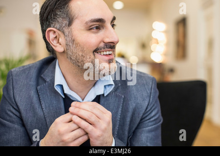 Lächelnd Mitte adult Geschäftsmann mit den Händen umklammert wegschauen im Büro Stockfoto