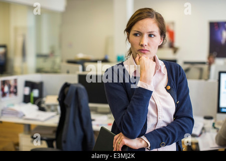 Nachdenklich Geschäftsfrau mit Hand am Kinn im Büro Stockfoto