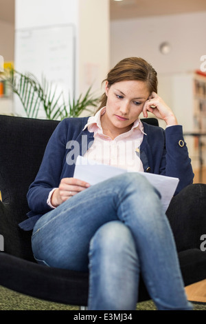 Mitte adult Geschäftsfrau lesen Dokument im Büro Stockfoto