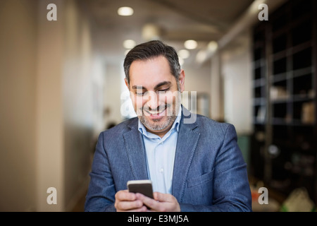 Lächelnd Geschäftsmann SMS auf Handy im Büro Stockfoto