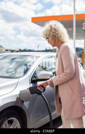 Seitenansicht des senior Frau Auto an Tankstelle tanken Stockfoto