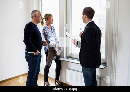 Männliche Immobilienmakler diskutieren mit paar zu Hause Stockfoto