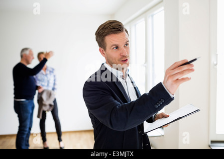 Immobilienmakler Haus mit paar diskutieren im Hintergrund prüfen Stockfoto