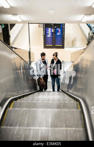 Volle Länge des Geschäftskollegen auf Rolltreppe in u-Bahnstation Stockfoto