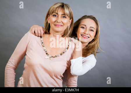 Spielerische schöne junge Mutter und ihre Tochter im Teenageralter posieren zusammen mit der jungen Mädchen spähen Out auf die Seite mit einem fröhlichen Stockfoto