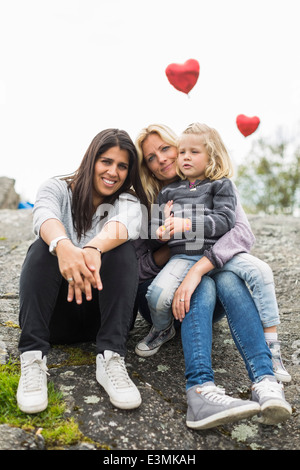 Porträt von glücklich weibliche Homosexuelle Familie entspannend auf Felsen Stockfoto