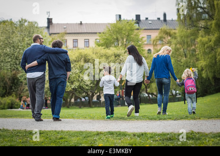 Rückansicht des weiblichen Homosexuellen Familie gehen im Park mit schwules Paar im Hintergrund Stockfoto