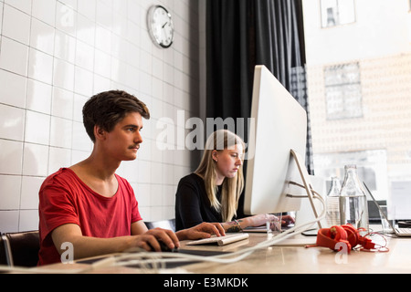 Junge Unternehmer und Unternehmerin mit Technologien im neuen Büro Stockfoto