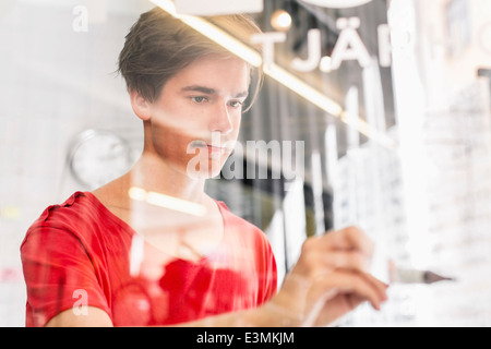 Junge Unternehmer schriftlich auf transparentem Glas im neuen Büro Stockfoto