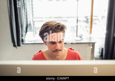 Konzentrierte junger Geschäftsmann mit Computer im neuen Büro Stockfoto