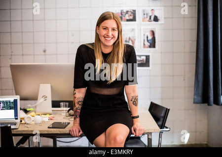 Porträt der lächelnde junge Geschäftsfrau lehnt sich am Tisch im neuen Büro Stockfoto