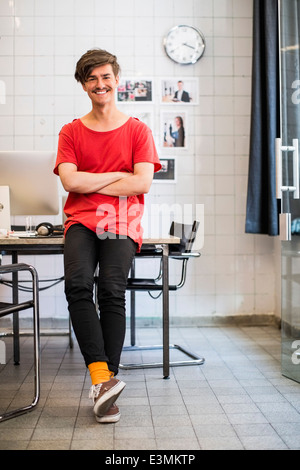 In voller Länge Portrait von lächelnden jungen Geschäftsmann mit Arme gekreuzt im neuen Büro Stockfoto