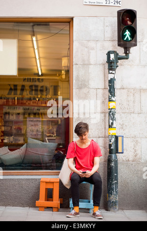 Gesamte Länge der junge Mann liest SMS auf Handy am Bürgersteig Stockfoto