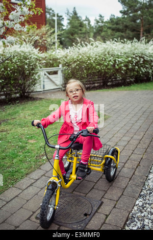 Porträt eines Mädchens mit Down-Syndrom mit Fahrrad in Rasen Stockfoto