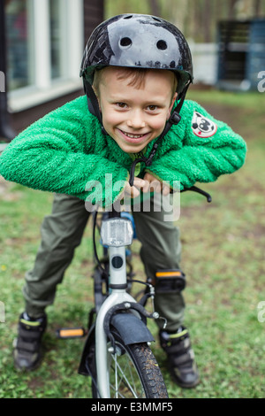 Porträt von fröhlicher Junge mit Helm und stützte sich auf dem Fahrrad Stockfoto