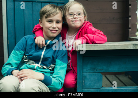 Porträt von Behinderten Mädchen mit Arm um Bruder sitzt auf der Veranda Stockfoto