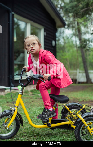 Porträt eines Mädchens mit Down-Syndrom mit Fahrrad in Rasen Stockfoto