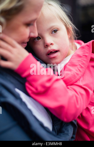 Mädchen mit Down-Syndrom von Mutter getragen Stockfoto