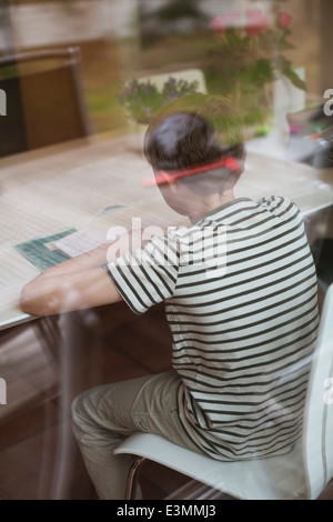 Ansicht des jungen studieren am Tisch durch Glas Stockfoto