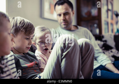 Geschwister mit Vater im Haus sitzen Stockfoto