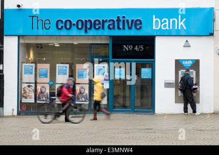 Ein Mann mit Cashpoint & Bewegung verwischt Passanten vorbei an Swindon Verzweigung der Co-Operative Bank Stockfoto