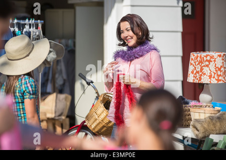 Frau versucht auf Federboa am Yard sale Stockfoto